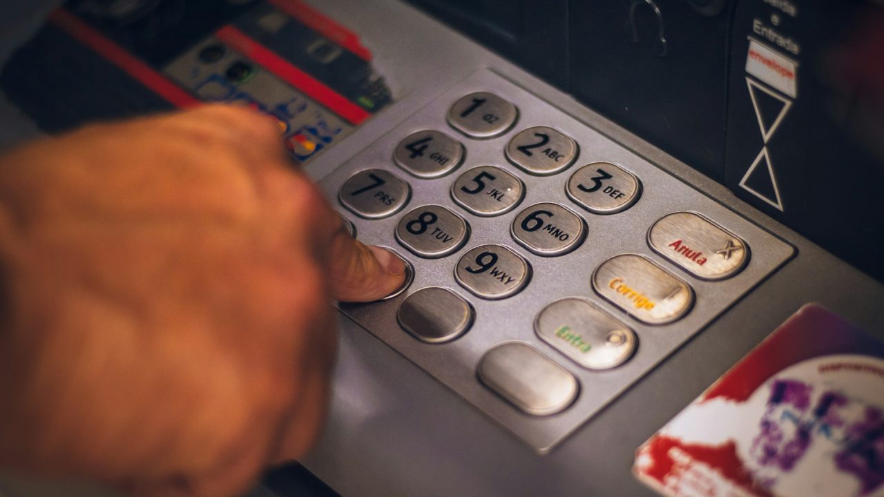 close up of a hand pushing buttons on an ATM