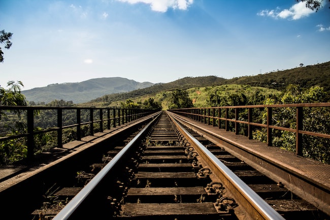a railroad in the foreground with rolling hills and blue sky in the background