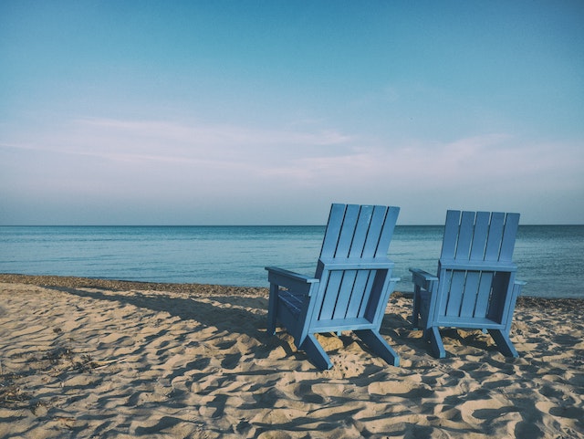 two beach chairs on the shore facing the ocean