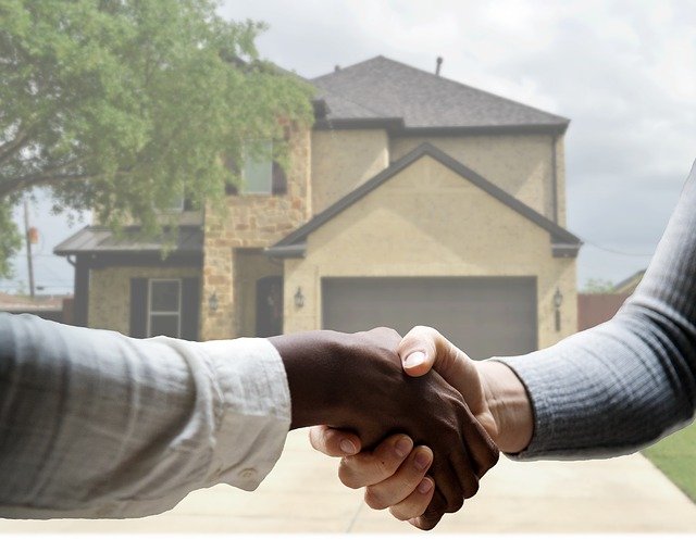 closeup of a handshake between two people with a house in the background