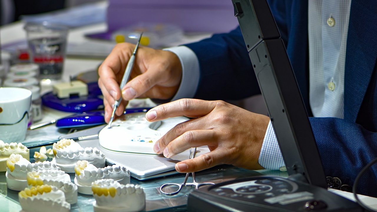 close up of a person's hands working on moulds of teeth