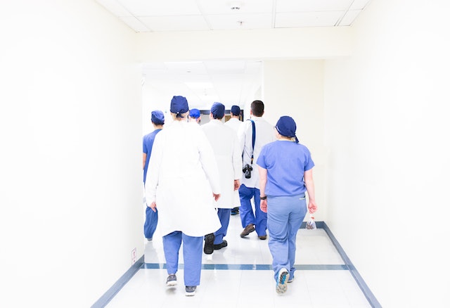 doctors and nurses walking down a sterile white hallway