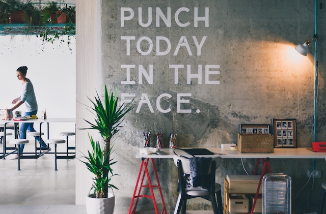 office with a worker in the background and a large sign that reads punch today in the face