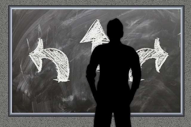 silhouette of man staring at a blackboard with three different directional arrows