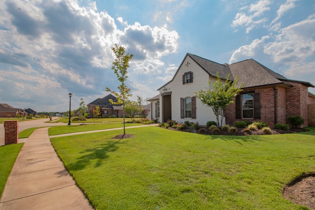 a single family home with a freshly cut lawn on a clouded sunny day
