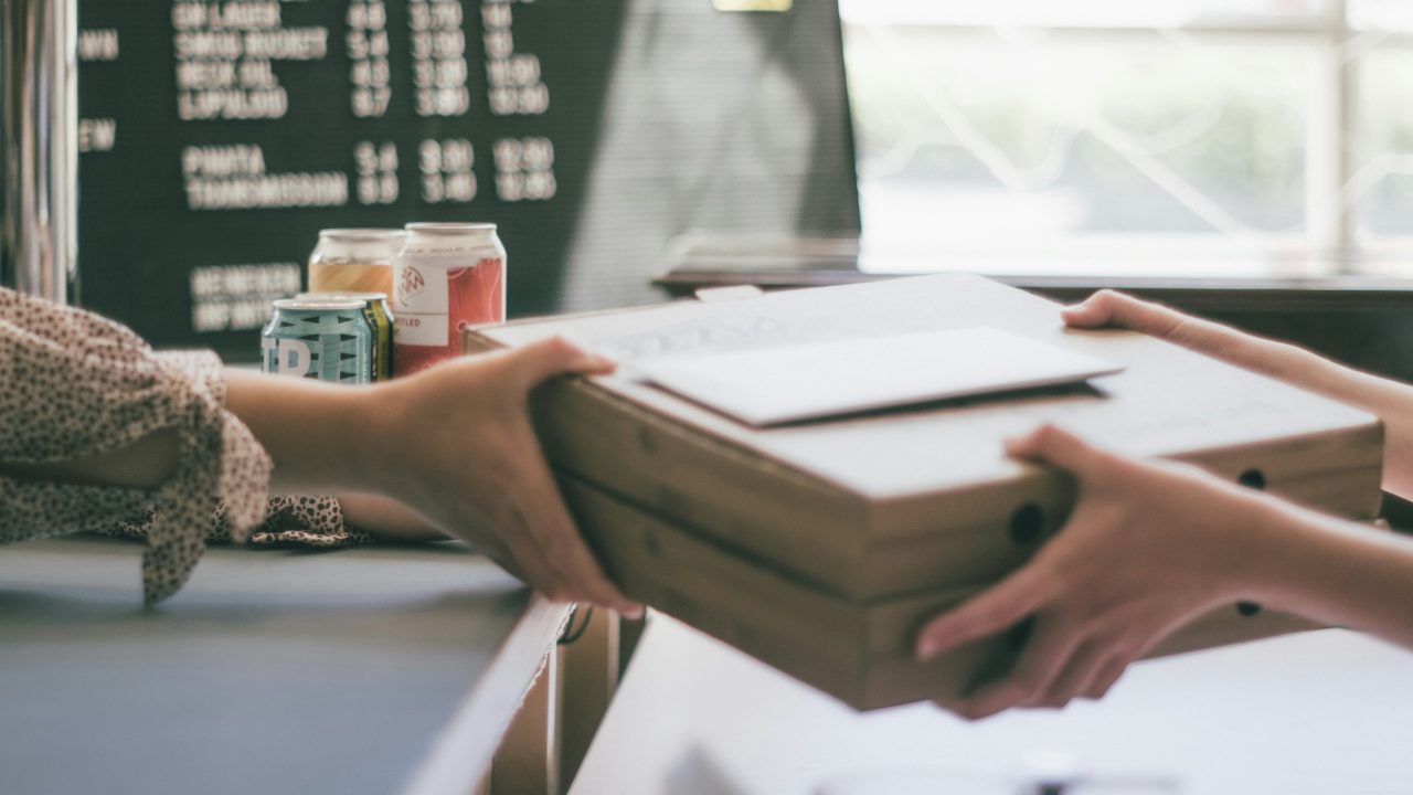 close-up of hands in front of a coffee menu exchanging binders of books