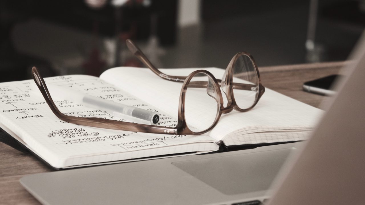 a pair of glasses resting atop an open journal with notes