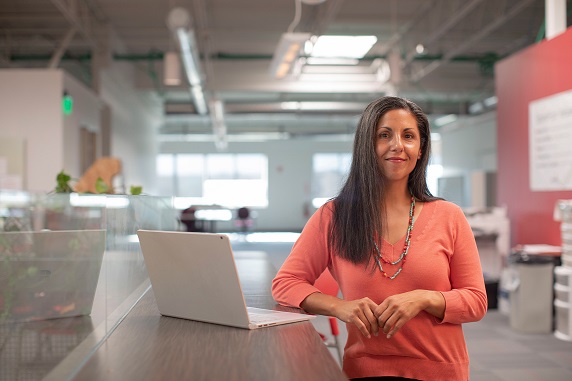 woman business owner in empty office with her laptop open on the counter.